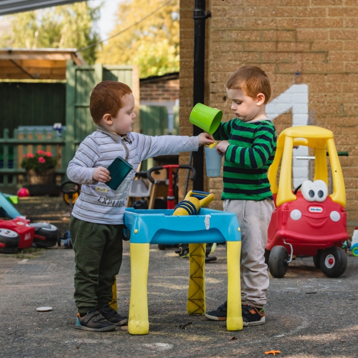 Image of two under-fives with some of the excellent outdoor equipment at Little Cedars nursery.