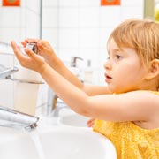 An under-five girl learns to wash her own hands.