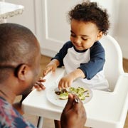 A father teaching his son to feed himself.